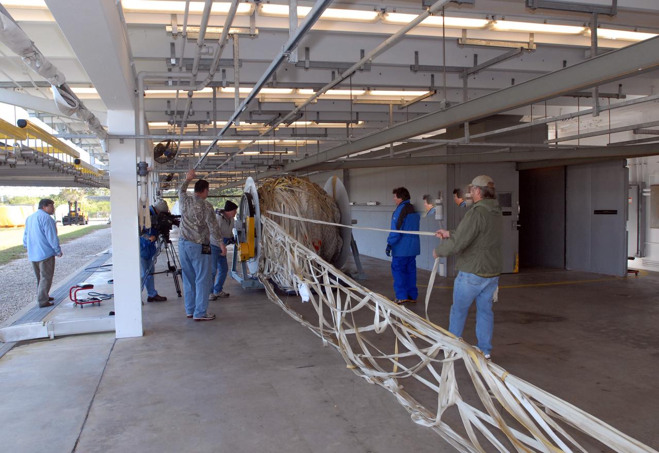 CAPE CANAVERAL, Fla. – At the Parachute Refurbishment Facility at NASA's Kennedy Space Center in Florida, another parachute recovered from sea after the launch of space shuttle Endeavour on the STS-126 mission is unwound from a large turnstile. After their recovery, the parachutes are untangled, hung on a monorail system and transported into a 30,000-gallon washer and a huge dryer heated with 140-degree air at 13,000 cubic feet per minute. The parachutes are used to slow the descent of the solid rocket boosters that are jettisoned during liftoff. One pilot, one drogue and three main canopies per booster slow the booster’s fall from about 360 mph to 50 mph. After the chutes are cleaned and repaired, they must be carefully packed into their bags so they will deploy correctly the next time they are used. Photo credit: NASA/Jim Grossmann
