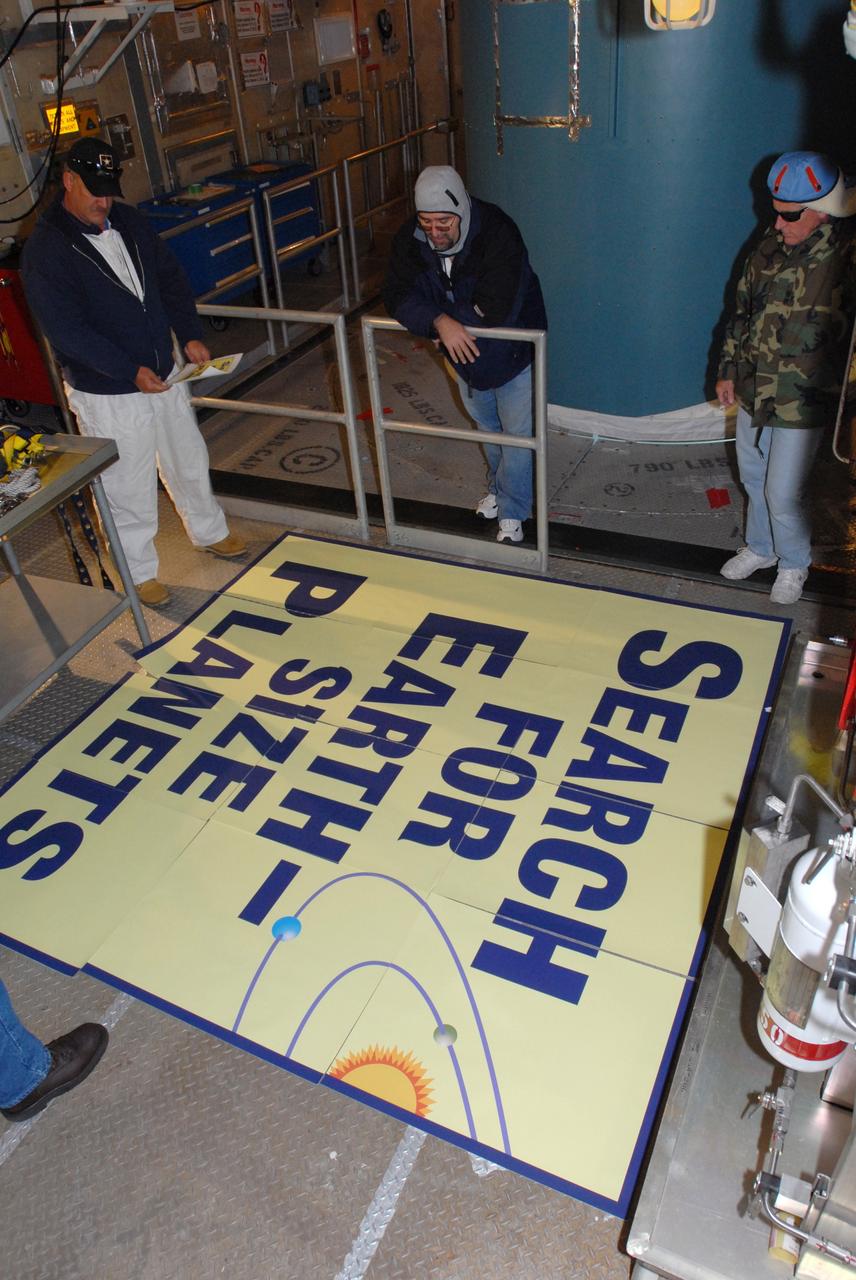CAPE CANAVERAL, Fla. – Workers at Launch Complex 17-B on Cape Canaveral Air Force Station in Florida check the large patch they will place on the Delta 2 rocket (behind them). The patch describes the Kepler spacecraft mission that will be launched by the rocket. The Kepler mission is specifically designed to survey our region of the Milky Way galaxy to discover hundreds of Earth-size and smaller planets in or near the habitable zone and determine how many of the billions of stars in our galaxy have such planets. Results from this mission will allow us to place our solar system within the continuum of planetary systems in the Galaxy. Photo credit: NASA/Jim Grossmann