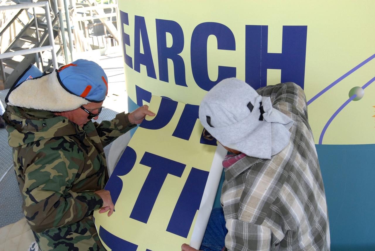 CAPE CANAVERAL, Fla. – Workers at Launch Complex 17-B on Cape Canaveral Air Force Station in Florida place sections of the large patch that describes the Kepler spacecraft mission to be launched by the Delta 2 rocket. The Kepler mission is specifically designed to survey our region of the Milky Way galaxy to discover hundreds of Earth-size and smaller planets in or near the habitable zone and determine how many of the billions of stars in our galaxy have such planets. Results from this mission will allow us to place our solar system within the continuum of planetary systems in the Galaxy. Photo credit: NASA/Jim Grossmann