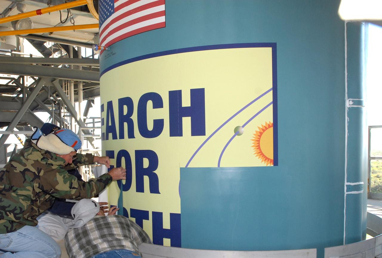 CAPE CANAVERAL, Fla. – Workers at Launch Complex 17-B on Cape Canaveral Air Force Station in Florida place the large patch on the Delta 2 rocket that describes the Kepler spacecraft mission to be launched by the rocket. The Kepler mission is specifically designed to survey our region of the Milky Way galaxy to discover hundreds of Earth-size and smaller planets in or near the habitable zone and determine how many of the billions of stars in our galaxy have such planets. Results from this mission will allow us to place our solar system within the continuum of planetary systems in the Galaxy. Photo credit: NASA/Jim Grossmann