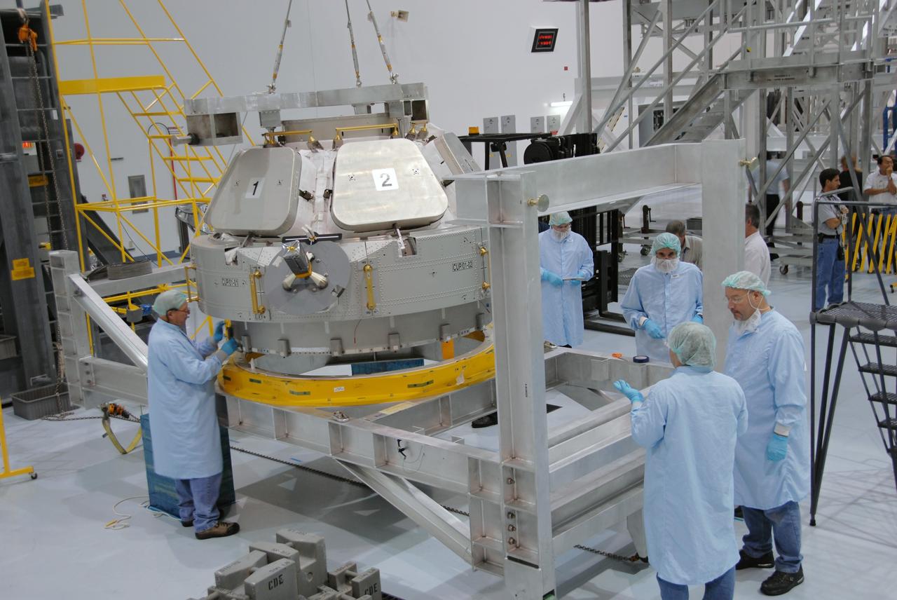 CAPE CANAVERAL, Fla. – Workers in the Space Station Processing Facility at NASA's Kennedy Space Center in Florida oversee placement of the Cupola module onto a workstand. The module was delivered to Kennedy by the European Space Agency in 2004 from Alenia Spazio in Turin, Italy. Cupola will provide a 360-degree panoramic view of activities outside the station and spectacular views of the Earth. Cupola has the capability for command and control workstations to be installed to assist in space station remote manipulator system and extra vehicular activities. The final element of the space station core, Cupola is scheduled for launch on space shuttle Endeavour's STS-130 mission, targeted for Dec. 10, 2009. Photo credit: NASA/Cory Huston
