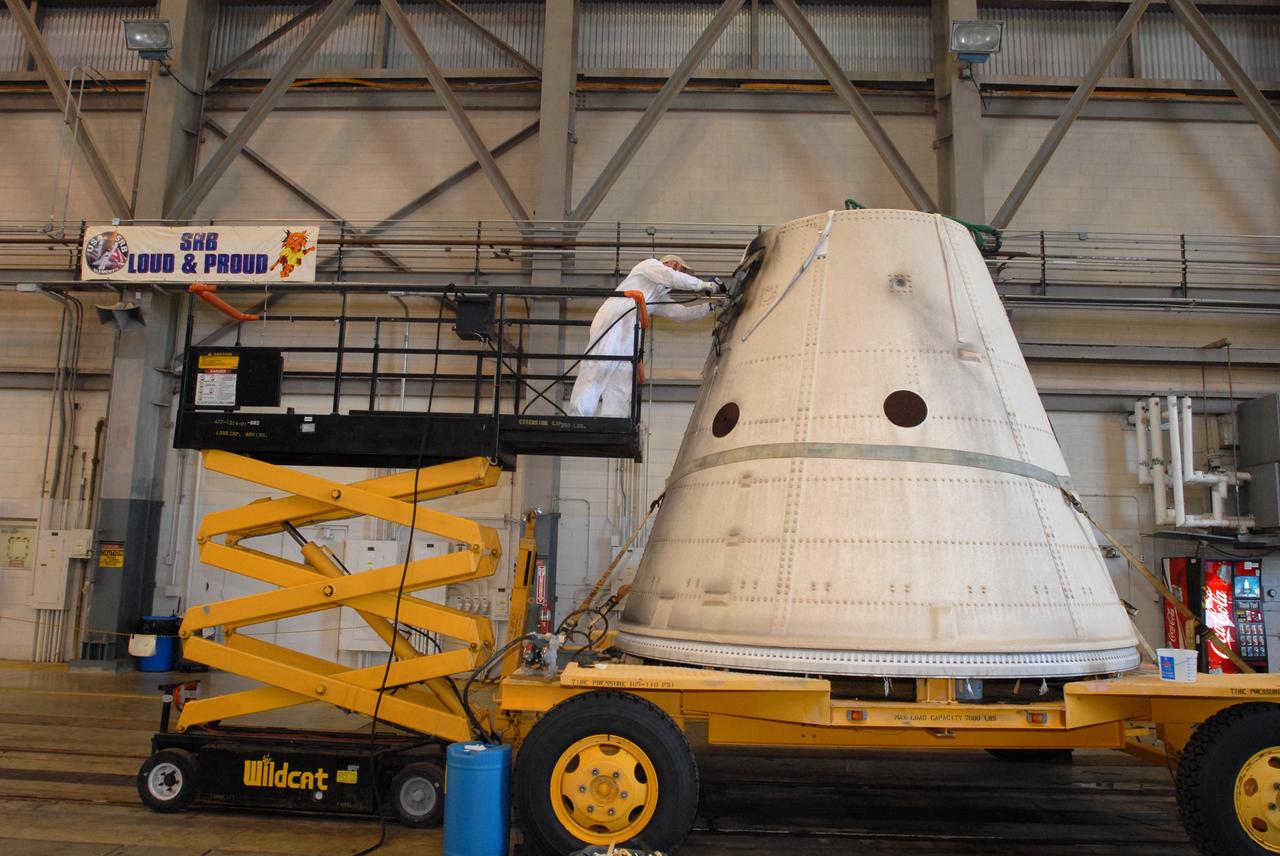 CAPE CANAVERAL, Fla. –   At Hangar AF at Cape Canaveral Air Force Station in Florida, a worker examines one of the frustums from two spent solid rocket boosters from space shuttle Endeavour, which launched Nov. 14 on the STS-126 mission. The frustum was offloaded from the solid rocket booster retrieval ship Freedom Star and moved inside the Hangar AF High Bay for disassembly. The space shuttle’s solid rocket booster casings and associated flight hardware are recovered at sea after being jettisoned. The boosters impact the Atlantic Ocean approximately seven minutes after liftoff. After their recovery and transport to Hangar AF, the boosters are cleaned, inspected, disassembled, refurbished and reloaded with solid propellant for reuse.  Photo credit: NASA/Jim Grossmann