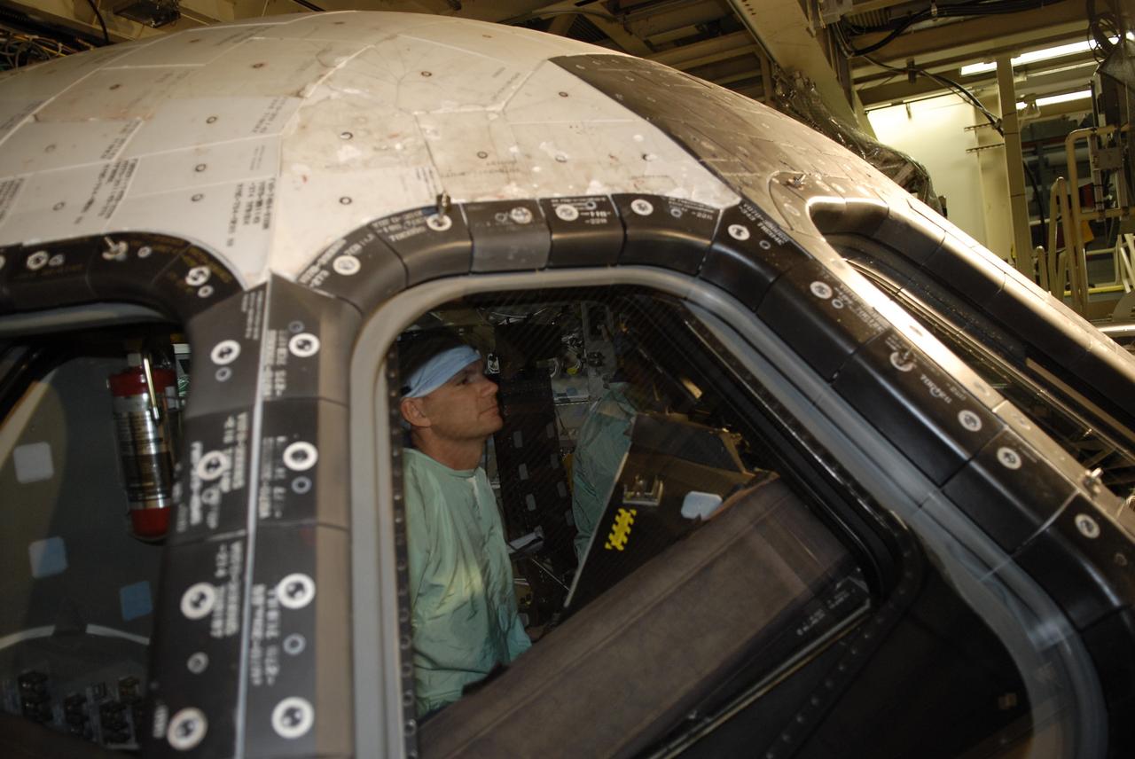 CAPE CANAVERAL, Fla. -- In the Orbiter Processing Facility at NASA's Kennedy Space Center in Florida, STS-119 Pilot Tony Antonelli checks the cockpit window of space shuttle Discovery. He and other crew members are at Kennedy for a Crew Equipment Interface Test that provides experience handling tools, equipment and hardware they will use on the mission. On the STS-119 mission, space shuttle Discovery will carry the S6 truss segment to complete the 361-foot-long backbone of the International Space Station. The truss includes the fourth pair of solar array wings and electronics that convert sunlight to power for the orbiting laboratory. Discovery is targeted for launch on Feb. 12, 2009. Photo credit: NASA/Kim Shiflett