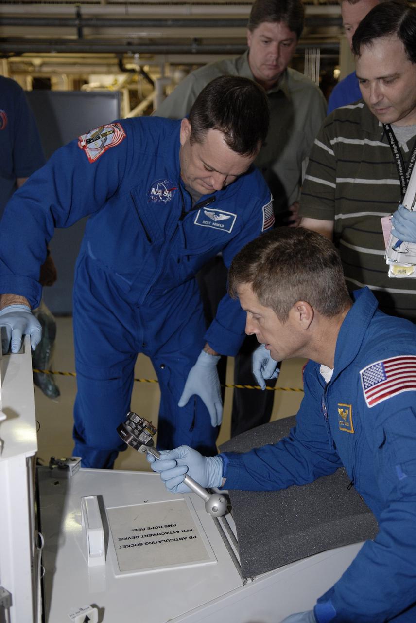 CAPE CANAVERAL, Fla. --  In the Orbiter Processing Facility at NASA's Kennedy Space Center in Florida, STS-119 Mission specialists Richard Arnold (left) and Steve Swanson handle tools to be used on the mission. The crew is at Kennedy for a Crew Equipment Interface Test that provides experience handling tools, equipment and hardware they will use on the mission.  On the STS-119 mission, space shuttle Discovery will carry the S6 truss segment to complete the 361-foot-long backbone of the International Space Station. The truss includes the fourth pair of solar array wings and electronics that convert sunlight to power for the orbiting laboratory.  Discovery is targeted for launch on Feb. 12, 2009. Photo credit: NASA/Kim Shiflett