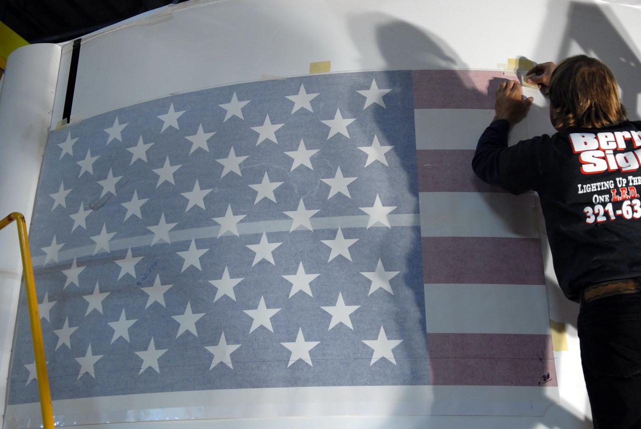 CAPE CANAVERAL, Fla. –  In the Vehicle Assembly Building high bay 4 at NASA's Kennedy Space Center in Florida, workers begin adhering a decal of the U.S. flag on one of the Ares I-X upper stage simulator segments. The upper stage simulator will be used in the test flight identified as Ares I-X in 2009.  Ares I-X is the test vehicle for the Ares I, which is part of the Constellation Program to return men to the moon and beyond.  Ares I is the essential core of a safe, reliable, cost-effective space transportation system that eventually will carry crewed missions back to the moon, on to Mars and out into the solar system. Ares I may also use its 25-ton payload capacity to deliver resources and supplies to the International Space Station, or to "park" payloads in orbit for retrieval by other spacecraft bound for the moon or other destinations.  Photo credit: NASA/Jack Pfaller