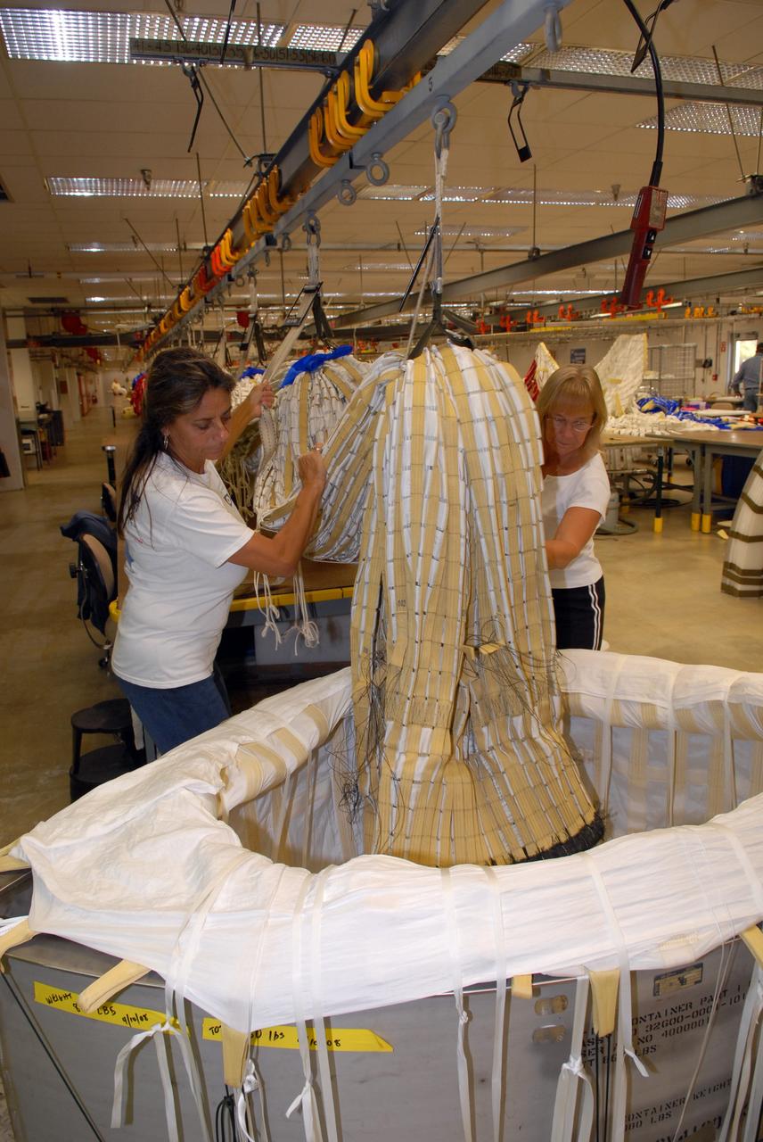 CAPE CANAVERAL, Fla. - In the Parachute Refurbishment Facility at NASA's Kennedy Space Center, United Space Alliance senior aero composite technicians Dior Hubel (left) and Marcia Jones-Clark begin to pack a main parachute slated for use on the Ares I-X test flight. The launch is targeted for July 2009 from Kennedy Space Center’s Launch Pad 39B and will provide an early opportunity to test and prove hardware, facilities and ground operations associated with the Ares I rocket. The Ares I-X rocket is a combination of existing and simulator hardware that will resemble the Ares I crew launch vehicle in size, shape and weight. It will provide valuable data to guide the final design of the Ares I, which will launch astronauts in the Orion crew exploration vehicle. The test flight also will bring NASA one step closer to its exploration goals of returning humans to the moon for sustained exploration of the lunar surface and missions to destinations beyond. Photo credit: NASA/Jack Pfaller