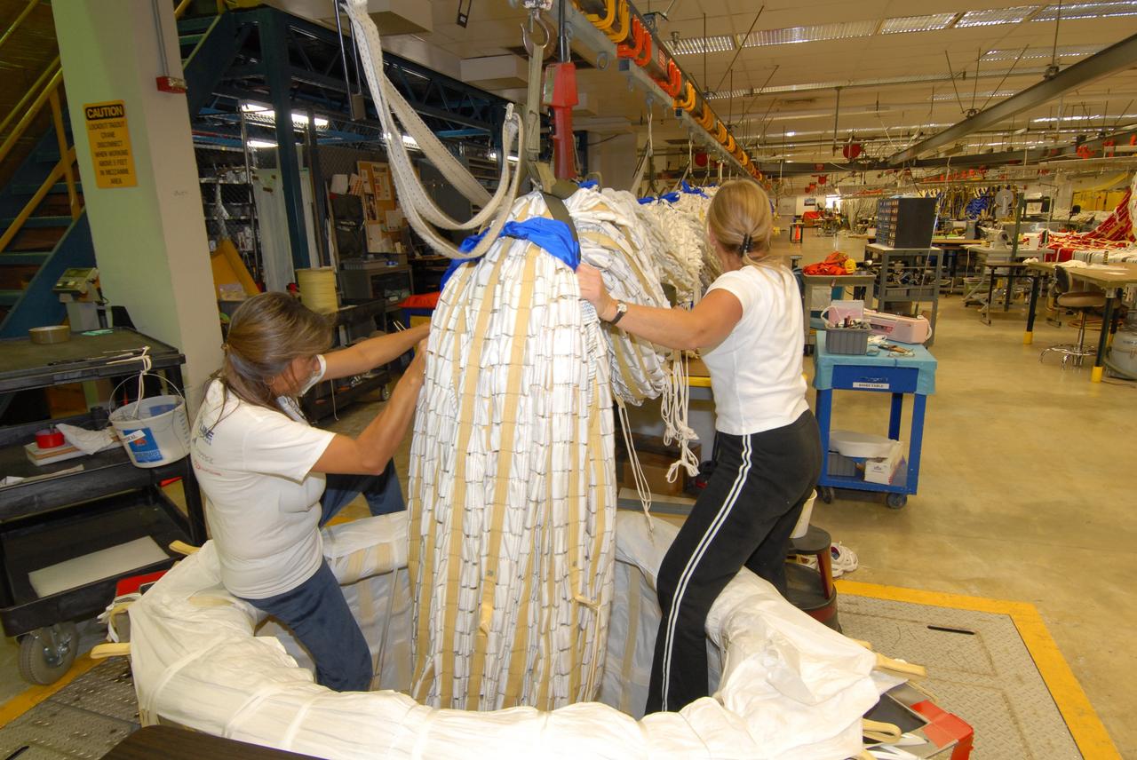 CAPE CANAVERAL, Fla. - In the Parachute Refurbishment Facility at NASA's Kennedy Space Center, United Space Alliance senior aero composite technicians Dior Hubel (left) and Marcia Jones-Clark pack a main parachute slated for use on the Ares I-X test flight. The launch is targeted for July 2009 from Kennedy’s Launch Pad 39B and will provide an early opportunity to test and prove hardware, facilities and ground operations associated with the Ares I rocket. The Ares I-X rocket is a combination of existing and simulator hardware that will resemble the Ares I crew launch vehicle in size, shape and weight. It will provide valuable data to guide the final design of the Ares I, which will launch astronauts in the Orion crew exploration vehicle. The test flight also will bring NASA one step closer to its exploration goals of returning humans to the moon for sustained exploration of the lunar surface and missions to destinations beyond. Photo credit: NASA/Jack Pfaller