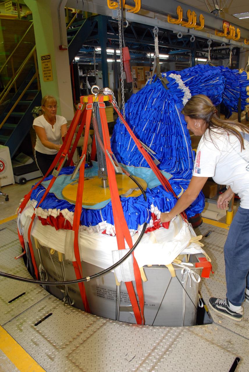 CAPE CANAVERAL, Fla. - In the Parachute Refurbishment Facility at NASA's Kennedy Space Center, United Space Alliance senior aero composite technicians Marcia Jones-Clark (left) and Dior Hubel pack a colorful main parachute slated for use on the Ares I-X test flight. The new parachutes are red, white and blue. The launch is targeted for July 2009 from Kennedy’s Launch Pad 39B and will provide an early opportunity to test and prove hardware, facilities and ground operations associated with the Ares I rocket. The Ares I-X rocket is a combination of existing and simulator hardware that will resemble the Ares I crew launch vehicle in size, shape and weight. It will provide valuable data to guide the final design of the Ares I, which will launch astronauts in the Orion crew exploration vehicle. The test flight also will bring NASA one step closer to its exploration goals of returning humans to the moon for sustained exploration of the lunar surface and missions to destinations beyond. Photo credit: NASA/Jack Pfaller