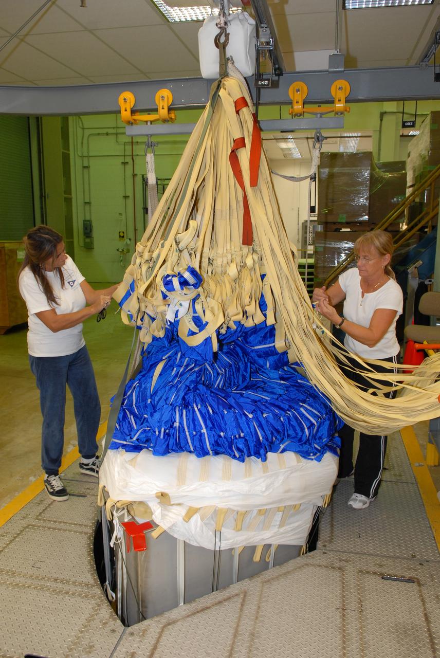 CAPE CANAVERAL, Fla. - In the Parachute Refurbishment Facility at NASA's Kennedy Space Center, United Space Alliance senior aero composite technicians Dior Hubel (left) and Marcia Jones-Clark pack a colorful main parachute slated for use on the Ares I-X test flight. The new parachutes are red, white and blue. The launch is targeted for July 2009 from Kennedy’s Launch Pad 39B and will provide an early opportunity to test and prove hardware, facilities and ground operations associated with the Ares I rocket. The Ares I-X rocket is a combination of existing and simulator hardware that will resemble the Ares I crew launch vehicle in size, shape and weight. It will provide valuable data to guide the final design of the Ares I, which will launch astronauts in the Orion crew exploration vehicle. The test flight also will bring NASA one step closer to its exploration goals of returning humans to the moon for sustained exploration of the lunar surface and missions to destinations beyond. Photo credit: NASA/Jack Pfaller