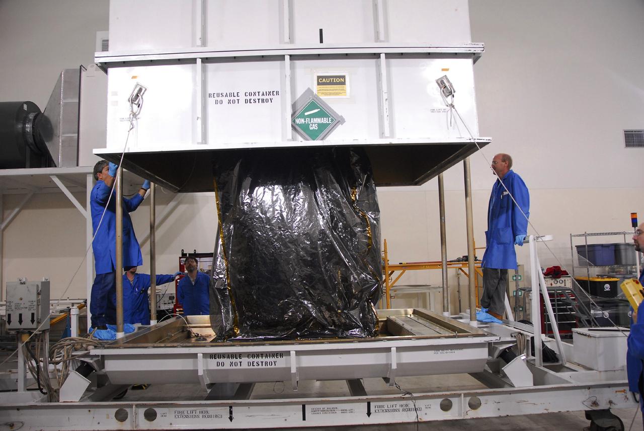 VANDENBERG AIR FORCE BASE, Calif. -- Inside the Astrotech payload processing facility, building 1032, at Vandenberg Air Force Base in California, workers remove the shipping container cover over the Orbiting Carbon Observatory, or OCO, spacecraft, delivered from spacecraft facilities in Dulles, Va., by Orbital Sciences. After the protective coverings over the spacecraft are removed, blanket preparations and edge taping will be done, followed by mechanical preparations and work on the electronic ground support equipment. The OCO is a new Earth-orbiting mission sponsored by NASA's Earth System Science Pathfinder Program. The observatory is targeted to launch Jan. 15 from Space Launch Complex 576-E at Vandenberg. Photo credit: NASA/Robert Hargreaves Jr., VAFB