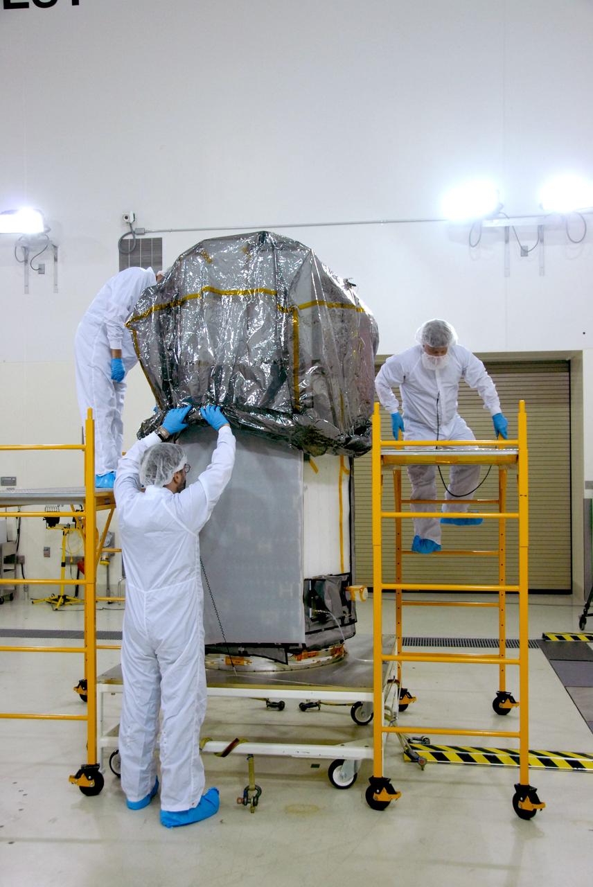 VANDENBERG AIR FORCE BASE, Calif. -- Inside the Astrotech payload processing facility, building 1032, at Vandenberg Air Force Base in California, workers remove the wrapping from around the Orbiting Carbon Observatory, or OCO. After the protective coverings over the spacecraft are removed, blanket preparations and edge taping will be done, followed by mechanical preparations and work on the electronic ground support equipment. The OCO is a new Earth-orbiting mission sponsored by NASA's Earth System Science Pathfinder Program. The observatory is targeted to launch Jan. 15 from Space Launch Complex 576-E at Vandenberg. Photo credit: NASA/Robert Hargreaves Jr., VAFB