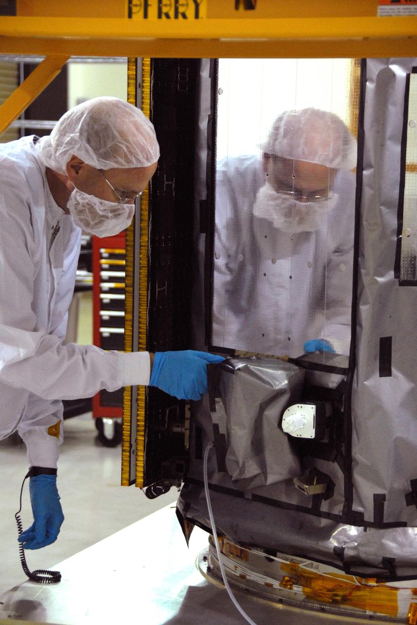 VANDENBERG AIR FORCE BASE, Calif. -- Inside the Astrotech payload processing facility, building 1032, at Vandenberg Air Force Base in California, workers apply blankets and edge tape to the Orbiting Carbon Observatory, or OCO. After the protective coverings over the spacecraft are removed, blanket preparations and edge taping will be done, followed by mechanical preparations and work on the electronic ground support equipment. The OCO is a new Earth-orbiting mission sponsored by NASA's Earth System Science Pathfinder Program. The observatory is targeted to launch Jan. 15 from Space Launch Complex 576-E at Vandenberg. Photo credit: NASA/Robert Hargreaves Jr., VAFB