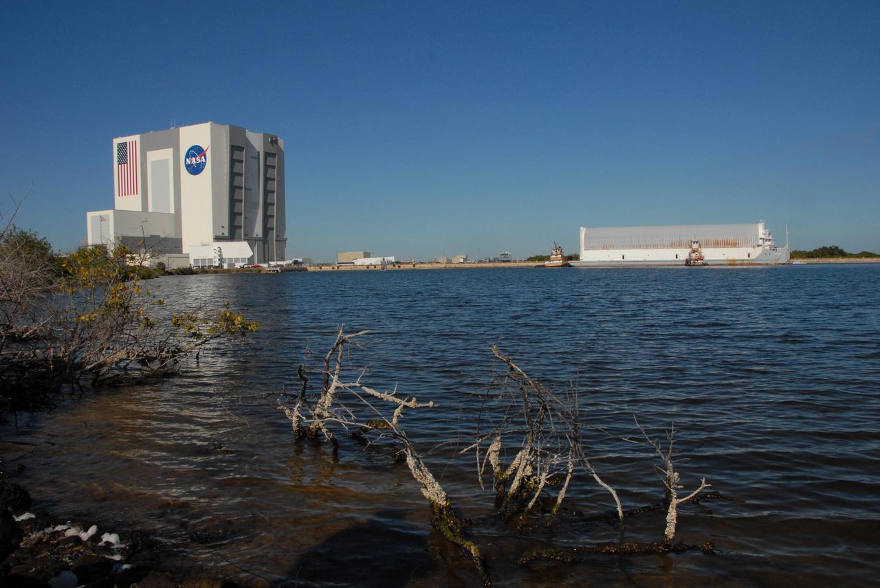 CAPE CANAVERAL, Fla. -- Towed by tugboats, the Pegasus barge with its cargo of external tank 130 nears the dock in the turn basis near the Vehicle Assembly Building, or VAB, at NASA's Kennedy Space Center in Florida. Pegasus arrived in Florida after an ocean voyage towed by a solid rocket booster retrieval ship from NASA's Michoud Assembly Facility near New Orleans. After the Pegasus docks, the fuel tank will be offloaded and transported to the VAB. External tank 130 is the one designated for space shuttle Endeavour on the STS-127 mission targeted for launch on May 15. Photo credit: NASA/Troy Cryder