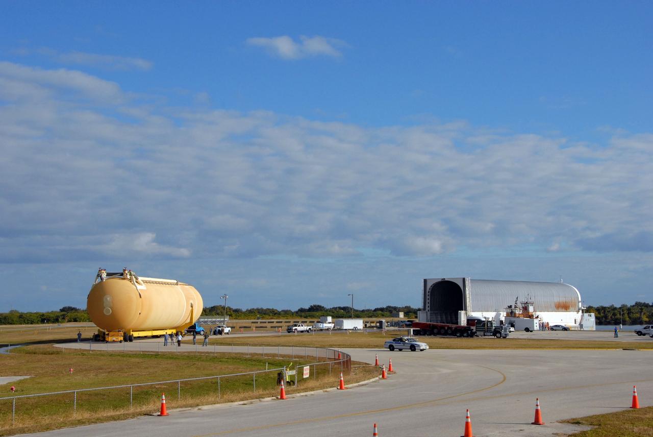 CAPE CANAVERAL, Fla. -- External Tank 130 is towed away from the turn basin at NASA's Kennedy Space Center in Florida. At right is the Pegasus barge that carried it from the Michoud Assembly Facility in New Orleans. ET 130, which will be used on the Hubble servicing mission, STS-125, is being moved to the Vehicle Assembly Building, seen at left, and into a high bay for checkout. The fuel tank was previously designated for the STS-127 mission. Photo credit: NASA/Jack Pfaller