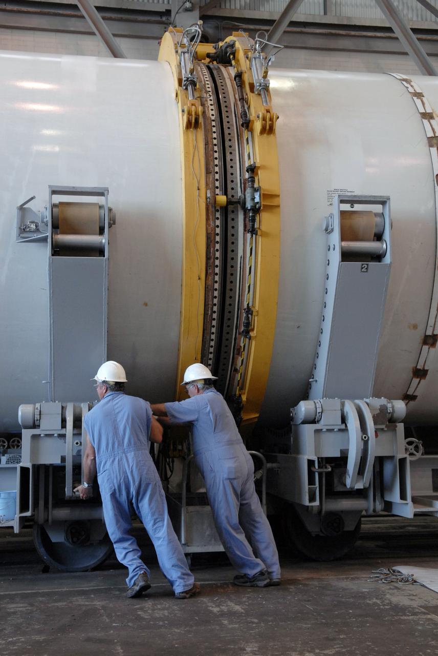 CAPE CANAVERAL, Fla. -- In Hangar AF at Cape Canaveral, Fla., with separation rings in place, workers begin to move apart segments of one of the retrieved solid rocket boosters from the STS-126 launch. The pins attaching the segments to each other are removed at the start. Each separation ring has three joints that help mold the ring around the segment and an air motor is used to rotate the rings to separate the segments. After disassembly, the segments will be sent to ATK (Alliant Techsystems) in Utah for final processing and return to Kennedy for another shuttle launch. Photo credit: NASA/Jack Pfaller