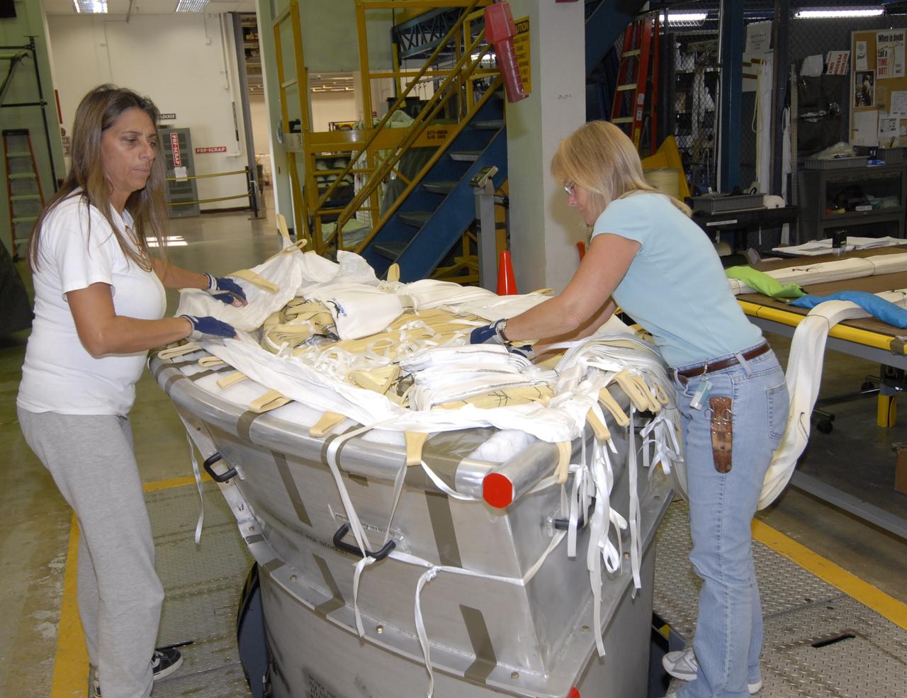 CAPE CANAVERAL, Fla. -- In the Parachute Refurbishment Facility at NASA's Kennedy Space Center in Florida, workers pack the parachutes that will be used in the Ares I-X development flight in July 2009. The first stage of the new Ares I rocket and Orion spacecraft will use parachutes to return to Earth. Ares I-X is the test vehicle for the Ares I, which is part of the Constellation Program to return men to the moon and beyond. Ares I is the essential core of a safe, reliable, cost-effective space transportation system that eventually will carry crewed missions back to the moon, on to Mars and out into the solar system. Ares I may also use its 25-ton payload capacity to deliver resources and supplies to the International Space Station, or to "park" payloads in orbit for retrieval by other spacecraft bound for the moon or other destinations. Photo credit: NASA/Jack Pfaller