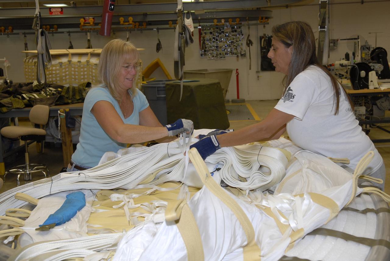 CAPE CANAVERAL, Fla. -- In the Parachute Refurbishment Facility at NASA's Kennedy Space Center in Florida, workers pack the parachutes that will be used in the Ares I-X development flight in July 2009. The first stage of the new Ares I rocket and Orion spacecraft will use parachutes to return to Earth. Ares I-X is the test vehicle for the Ares I, which is part of the Constellation Program to return men to the moon and beyond. Ares I is the essential core of a safe, reliable, cost-effective space transportation system that eventually will carry crewed missions back to the moon, on to Mars and out into the solar system. Ares I may also use its 25-ton payload capacity to deliver resources and supplies to the International Space Station, or to "park" payloads in orbit for retrieval by other spacecraft bound for the moon or other destinations. Photo credit: NASA/Jack Pfaller