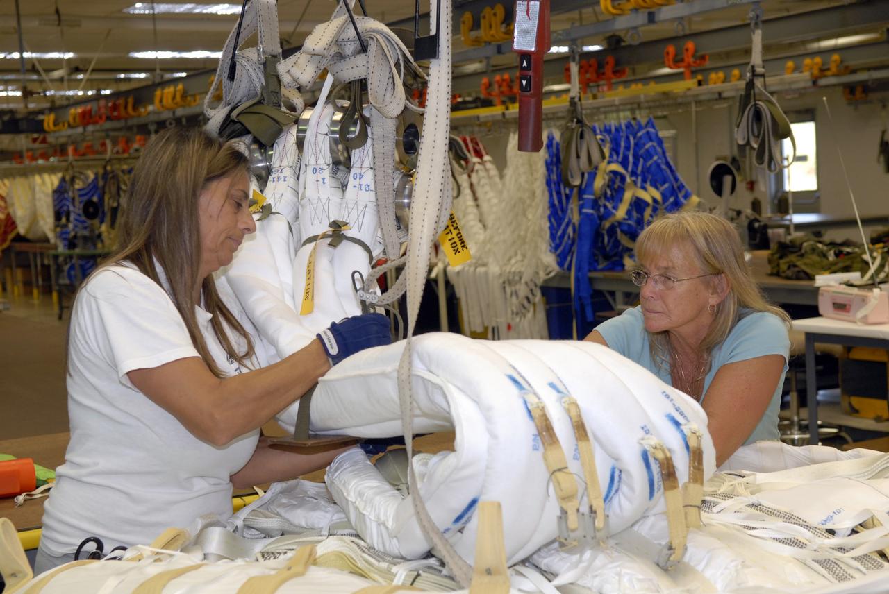 CAPE CANAVERAL, Fla. -- In the Parachute Refurbishment Facility at NASA's Kennedy Space Center in Florida, workers pack the parachutes that will be used in the Ares I-X development flight in July 2009. The first stage of the new Ares I rocket and Orion spacecraft will use parachutes to return to Earth. Ares I-X is the test vehicle for the Ares I, which is part of the Constellation Program to return men to the moon and beyond. Ares I is the essential core of a safe, reliable, cost-effective space transportation system that eventually will carry crewed missions back to the moon, on to Mars and out into the solar system. Ares I may also use its 25-ton payload capacity to deliver resources and supplies to the International Space Station, or to "park" payloads in orbit for retrieval by other spacecraft bound for the moon or other destinations. Photo credit: NASA/Jack Pfaller