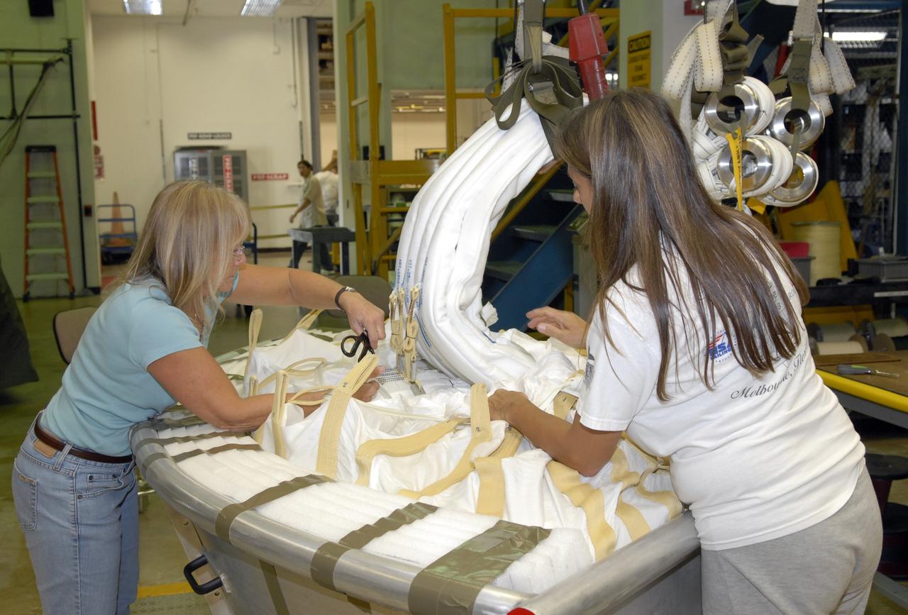 CAPE CANAVERAL, Fla. -- In the Parachute Refurbishment Facility at NASA's Kennedy Space Center in Florida, workers pack the parachutes that will be used in the Ares I-X development flight in July 2009. The first stage of the new Ares I rocket and Orion spacecraft will use parachutes to return to Earth. Ares I-X is the test vehicle for the Ares I, which is part of the Constellation Program to return men to the moon and beyond. Ares I is the essential core of a safe, reliable, cost-effective space transportation system that eventually will carry crewed missions back to the moon, on to Mars and out into the solar system. Ares I may also use its 25-ton payload capacity to deliver resources and supplies to the International Space Station, or to "park" payloads in orbit for retrieval by other spacecraft bound for the moon or other destinations. Photo credit: NASA/Jack Pfaller