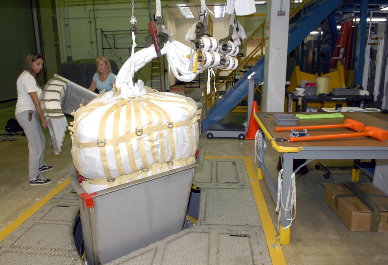 CAPE CANAVERAL, Fla. -- In the Parachute Refurbishment Facility at NASA's Kennedy Space Center in Florida, workers pack the parachutes that will be used in the Ares I-X development flight in July 2009. The first stage of the new Ares I rocket and Orion spacecraft will use parachutes to return to Earth. Ares I-X is the test vehicle for the Ares I, which is part of the Constellation Program to return men to the moon and beyond. Ares I is the essential core of a safe, reliable, cost-effective space transportation system that eventually will carry crewed missions back to the moon, on to Mars and out into the solar system. Ares I may also use its 25-ton payload capacity to deliver resources and supplies to the International Space Station, or to "park" payloads in orbit for retrieval by other spacecraft bound for the moon or other destinations. Photo credit: NASA/Jack Pfaller