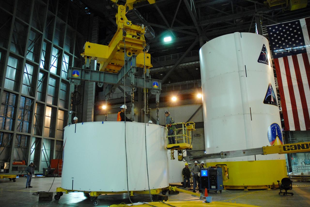 CAPE CANAVERAL, Fla. --  In high bay 4 of the Vehicle Assembly Building at NASA's Kennedy Space Center in Florida, a crane is attached to segment 5 of the Ares I-X upper stage simulator segments to lift it.  Segment 5 will be stacked on to segment 4, at the top of the tall stack at right.The upper stage simulator comprises 11 segments, each approximately 18 feet in diameter, that will be used in the test flight known as Ares I-X in 2009.  The simulator segments will simulate the mass and the outer mold line.  The upper stage accounts for nearly one-quarter of the total height of the Ares I.  It will take the Ares I on the second phase of its journey from Earth, providing the guidance, navigation and control needed for the second phase of the Ares I ascent flight.   Photo credit: NASA/Jim Grossmann