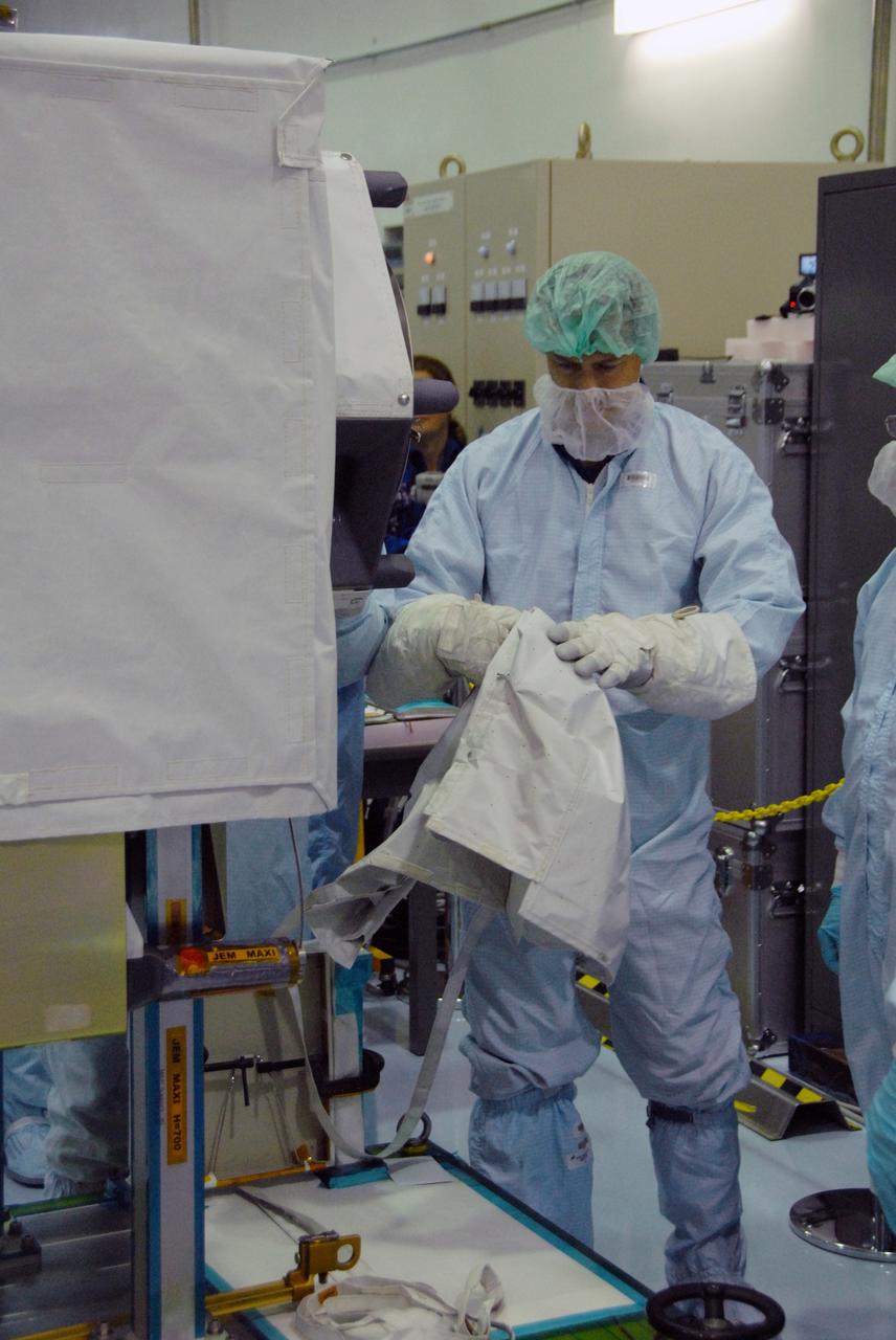 CAPE CANAVERAL, Fla. --  In the Space Station Processing Facility at NASA's Kennedy Space Center in Florida, a STS-127 crew member removes a portion of the cover on the MAXI (Monitor of All-Sky X-Ray Image), part of the payload for the mission.  The crew members are at Kennedy for a crew equipment interface test, or CEIT, which provides experience handling tools, equipment and hardware they will use on the mission. The payload will be launched to the International Space Station aboard space shuttle Endeavour on the STS-127 mission, targeted for launch on May 15, 2009. Photo credit: NASA/Dimitrios Gerondidakis