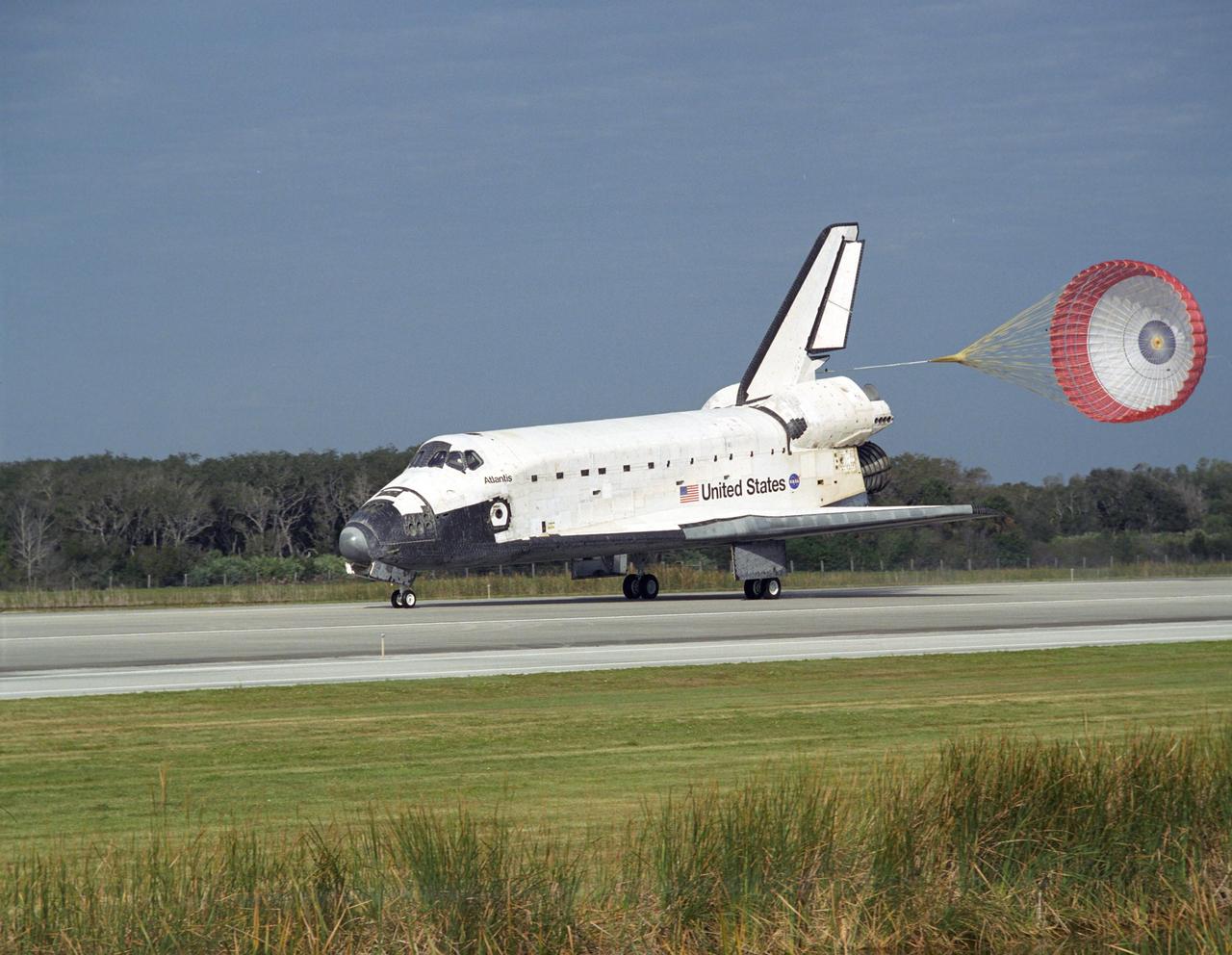 KENNEDY SPACE CENTER, FLA. -- With the aid of a drag chute, space shuttle Atlantis slows down after landing on Runway 15 of the Shuttle Landing Facility at NASA's Kennedy Space Center after a nearly 5.3 million mile round trip to the International Space Station. In the background is Launch Pad 39B. The shuttle landed on orbit 202 to complete the 13-day STS-122 mission. Main gear touchdown was 9:07:10 a.m. Nose gear touchdown was 9:07:20 a.m. Wheel stop was at 9:08:08 a.m. Mission elapsed time was 12 days, 18 hours, 21 minutes and 44 seconds. During the mission, Atlantis' crew installed the new Columbus laboratory, leaving a larger space station and one with increased science capabilities. The Columbus Research Module adds nearly 1,000 cubic feet of habitable volume and affords room for 10 experiment racks, each an independent science lab. Photo credit: NASA/Sandy Joseph, Tim Powers