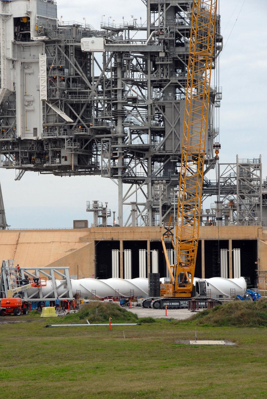 CAPE CANAVERAL, Fla. –  On Launch Pad 39B at NASA's Kennedy Space Center in Florida, equipment surrounds the service structures for the construction of towers in the new lightning protection system for the Constellation Program and Ares/Orion launches. In the foreground is part of the giant crane used to place segments on the towers. Each of the three new lightning towers will be 500 feet tall with an additional 100-foot fiberglass mast (seen on the ground) atop supporting a wire catenary system. This improved lightning protection system allows for the taller height of the Ares I rocket compared to the space shuttle. Pad 39B will be the site of the first Ares vehicle launch, including the Ares I-X test flight that is targeted for July 2009. Photo credit: NASA/Troy Cryder