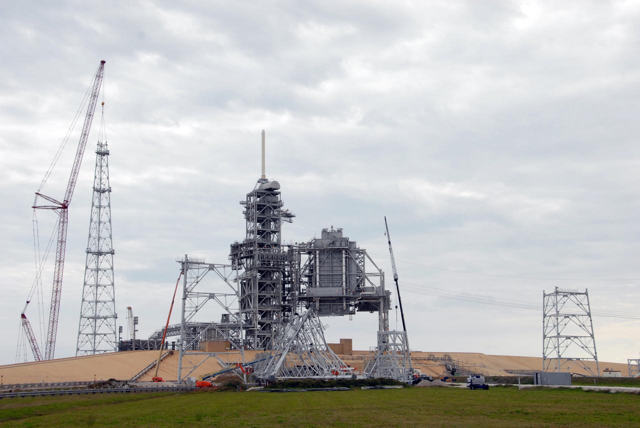 CAPE CANAVERAL, Fla. –  On Launch Pad 39B at NASA's Kennedy Space Center in Florida, a crane (at left) completes construction of one of the towers in the new lightning protection system for the Constellation Program and Ares/Orion launches. At right, another tower is being constructed. Each of the three new lightning towers will be 500 feet tall with an additional 100-foot fiberglass mast atop supporting a wire catenary system. This improved lightning protection system allows for the taller height of the Ares I rocket compared to the space shuttle. Pad 39B will be the site of the first Ares vehicle launch, including the Ares I-X test flight that is targeted for July 2009. Photo credit: NASA/Troy Cryder