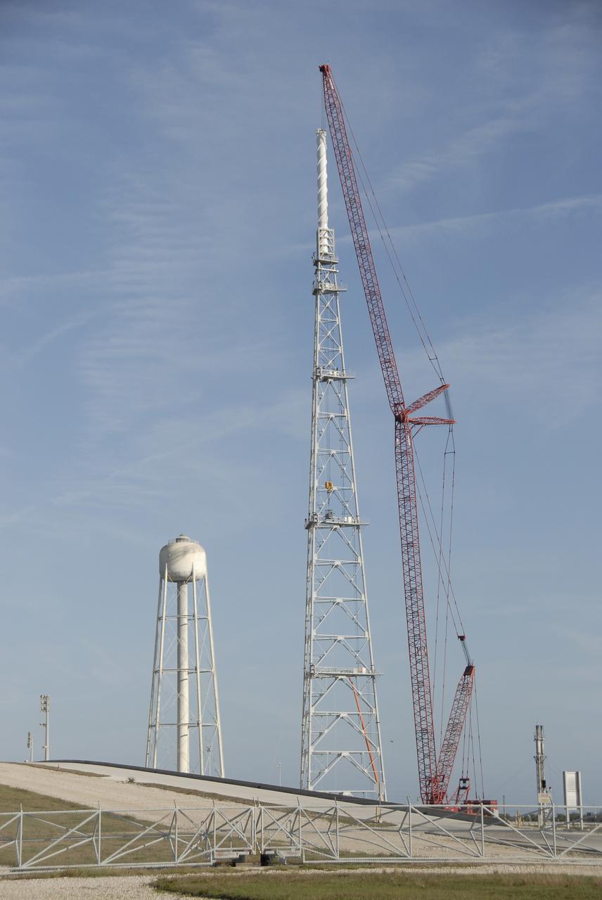 CAPE CANAVERAL, Fla. –  On Launch Pad 39B at NASA's Kennedy Space Center in Florida, a crane places the 100-foot fiberglass mast atop the new lightning tower constructed on the pad. The towers are part of the new lightning protection system for the Constellation Program and Ares/Orion launches. Each of the three new lightning towers will be 500 feet tall with the additional 100-foot fiberglass mast atop supporting a wire catenary system. This improved lightning protection system allows for the taller height of the Ares I rocket compared to the space shuttle. Pad 39B will be the site of the first Ares vehicle launch, including the Ares I-X test flight that is targeted for July 2009. Photo credit: NASA/Kim Shiflett