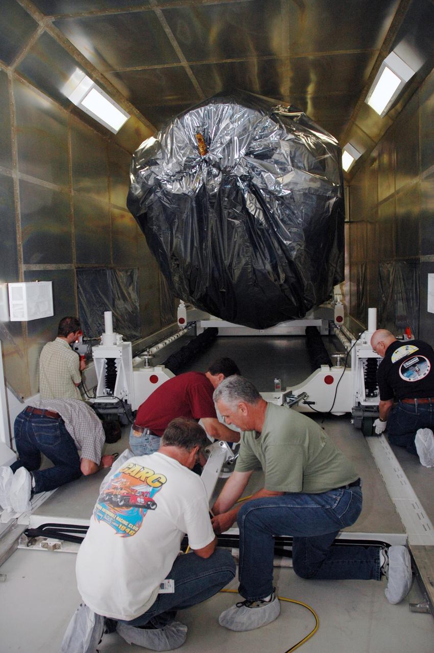 CAPE CANAVERAL, Fla. -- At the Astrotech payload processing facility in Titusville, Fla., workers prepare the mobile stand for removal of NASA's Kepler spacecraft from its shipping container. After its removal, the spacecraft will be rotated to vertical, uncovered and prepared for initial testing. A NASA Discovery mission, Kepler is specifically designed to survey our region of the Milky Way galaxy to discover hundreds of Earth-size and smaller planets in or near the habitable zone and determine how many of the billions of stars in our galaxy have such planets. Results from this mission will allow us to place our solar system within the continuum of planetary systems in the Galaxy. After processing at Astrotech, Kepler will be carried to its launch pad at Cape Canaveral. NASA's planet-hunting Kepler mission is scheduled to launch no earlier than March 5 atop a Delta II rocket. Photo credit: NASA/Chris Rhodes