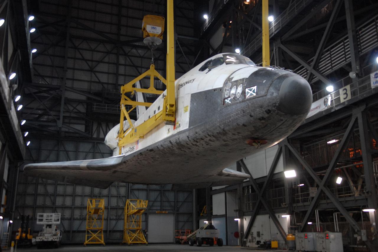 CAPE CANAVERAL, Fla. -- In the Vehicle Assembly Building at NASA's Kennedy Space Center in Florida, space shuttle Discovery is lifted away from its transporter above the transfer aisle. The shuttle will be raised to a vertical position and lifted into high bay 3 where it will be mated with its external fuel tank and solid rocket boosters on the mobile launcher platform. After additional preparations are made, the shuttle will be rolled out to Launch Pad 39A for a targeted launch on Feb. 12. Discovery will carry the final starboard truss (S6) in the assembly of the International Space Station. Photo credit: NASA/Troy Cryder