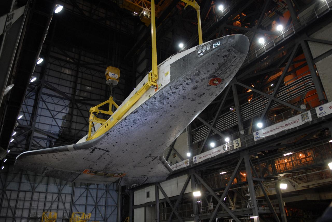 CAPE CANAVERAL, Fla. -- In the Vehicle Assembly Building at NASA's Kennedy Space Center in Florida, space shuttle Discovery is lifted above the transfer aisle. The shuttle will be raised to a vertical position and lifted into high bay 3 where it will be mated with its external fuel tank and solid rocket boosters on the mobile launcher platform. After additional preparations are made, the shuttle will be rolled out to Launch Pad 39A for a targeted launch on Feb. 12. Discovery will carry the final starboard truss (S6) in the assembly of the International Space Station. Photo credit: NASA/Jack Pfaller