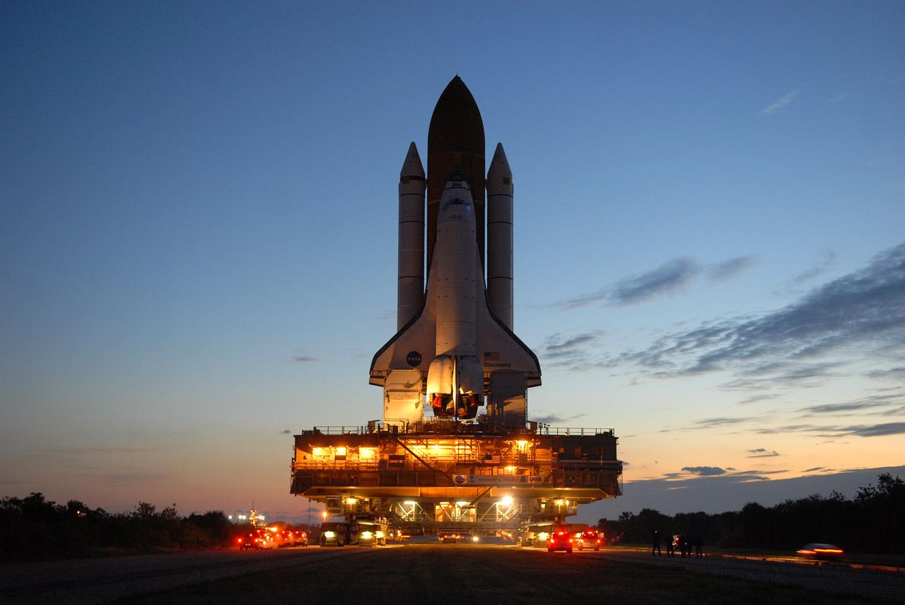 CAPE CANAVERAL, Fla. -- Space shuttle Discovery is silhouetted against the dawn's early light as it makes the slow 3.4-mile journey to Launch Pad 39A. The shuttle sits atop the mobile launcher platform, which are being moved by the massive crawler-transporter beneath. First motion out of the Vehicle Assembly Building was at 5:17 a.m. EST. Discovery is targeted to launch to the International Space Station Feb. 12. During Discovery's 14-day mission, the crew will install the S6 truss segment and its solar arrays to the starboard side of the station, completing the station's backbone, or truss, enabling a six-person crew to live there starting in May. Photo credit: NASA/Troy Cryder