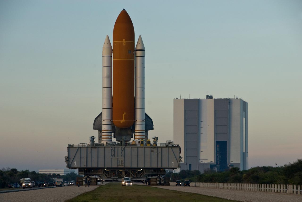 CAPE CANAVERAL, Fla. -- Space shuttle Discovery, atop the mobile launcher platform, makes the slow 3.4-mile journey via the broad, two-track crawlerway to Launch Pad 39A at NASA's Kennedy Space Center in Florida. First motion out of the Vehicle Assembly Building (at right) was at 5:17 a.m. EST. Discovery is targeted to launch to the International Space Station Feb. 12. During Discovery's 14-day mission, the crew will install the S6 truss segment and its solar arrays to the starboard side of the station, completing the station's backbone, or truss, enabling a six-person crew to live there starting in May. Photo credit: NASA/Troy Cryder