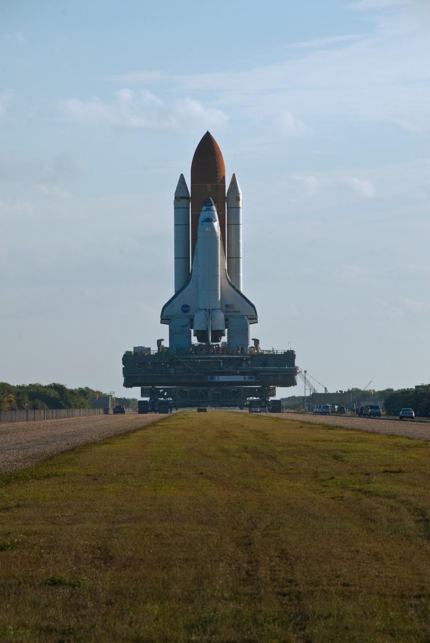 CAPE CANAVERAL, Fla. -- Space Space shuttle Discovery, atop the mobile launcher platform, makes the slow 3.4-mile journey via the broad, two-track crawlerway to Launch Pad 39A at NASA's Kennedy Space Center in Florida. First motion out of the Vehicle Assembly Building (at right) was at 5:17 a.m. EST. Discovery is targeted to launch to the International Space Station Feb. 12. During Discovery's 14-day mission, the crew will install the S6 truss segment and its solar arrays to the starboard side of the station, completing the station's backbone, or truss, enabling a six-person crew to live there starting in May. Photo credit: NASA/Troy Cryder