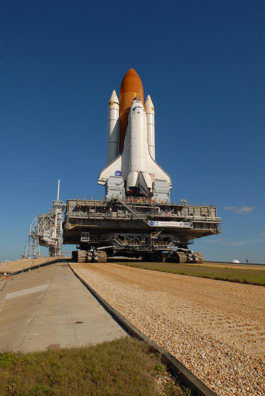 CAPE CANAVERAL, Fla. -- Space shuttle Discovery, atop the mobile launcher platform and crawler-transporter, climbs the ramp to Launch Pad 39A at NASA's Kennedy Space Center in Florida.  A laser guidance system and a leveling system on the crawler keeps the shuttle level as it moves up the ramp. At left is seen the fixed service structure with the 80-foot lightning mast on top. First motion out of the Vehicle Assembly Building was at 5:17 a.m. EST.  Discovery was secured to the pad at 12:16 p.m.  Discovery is targeted to launch to the International Space Station Feb. 12. During Discovery's 14-day mission, the crew will install the S6 truss segment and its solar arrays to the starboard side of the station, completing the station's backbone, or truss, enabling a six-person crew to live there starting in May.  Photo credit: NASA/Troy Cryder