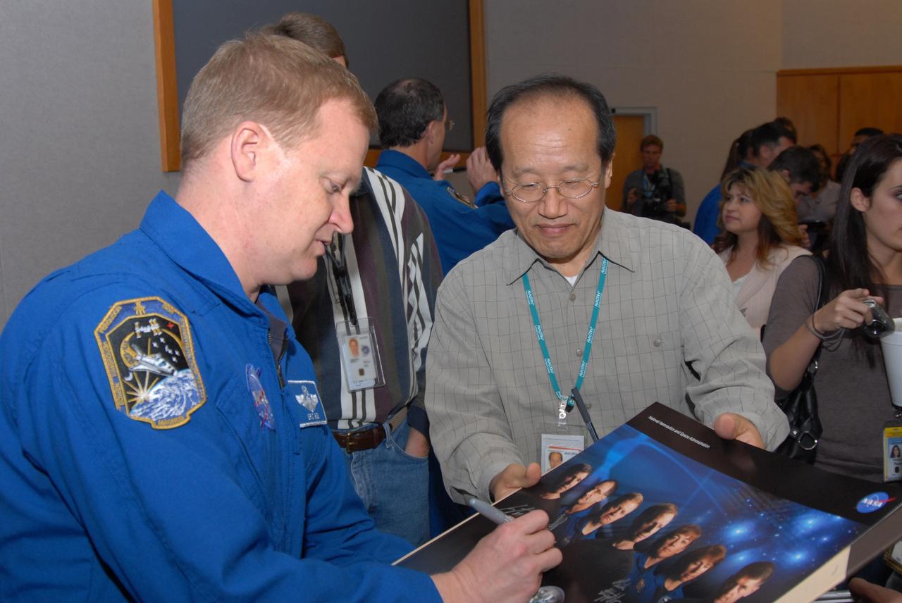 CAPE CANAVERAL, Fla. – At NASA's Kennedy Space Center in Florida, STS-126 crew members sign autographs and chat with Kennedy workers after the astronauts' presentation of their experiences during the mission. Here, Pilot Eric Boe autographs a picture of the crew. Photo credit: NASA/Dimitrios Gerondidakis
