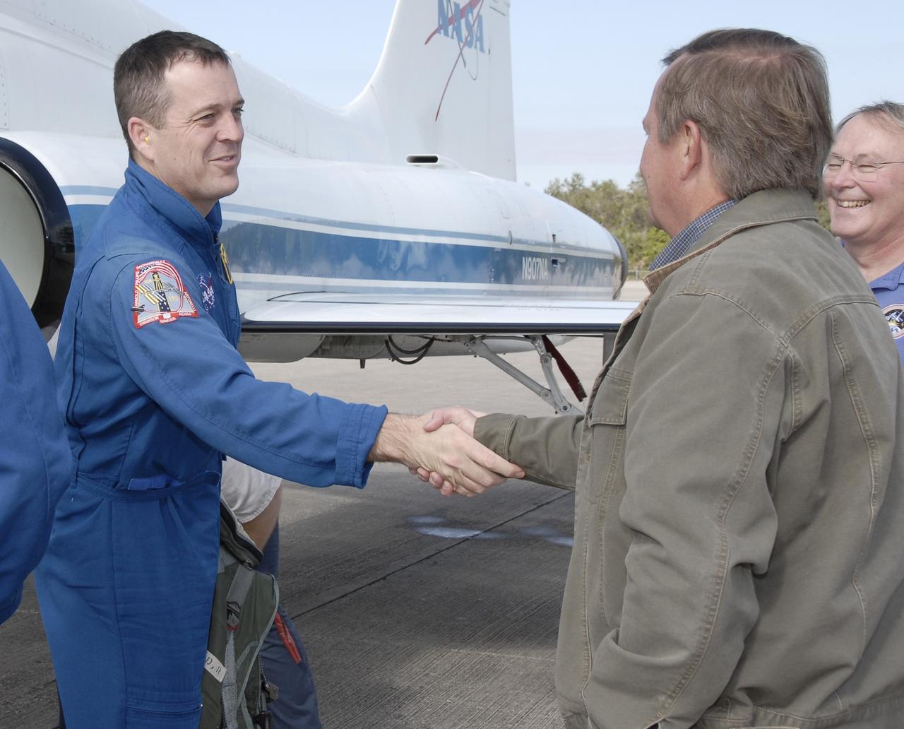 CAPE CANAVERAL, Fla. –   On the Shuttle Landing Facility at NASA's Kennedy Space Center in Florida, STS-119 Mission Specialist Richard Arnold is greeted by Shuttle Launch Director Mike Leinbach.  Next to Leinbach is Jerry Ross, chief of the Vehicle Integration Test Office. The crew flew to Kennedy to take part in terminal countdown demonstration test activities, which include equipment familiarization and emergency exit training and culminate in a simulated launch countdown. Photo credit: NASA/Kim Shiflett