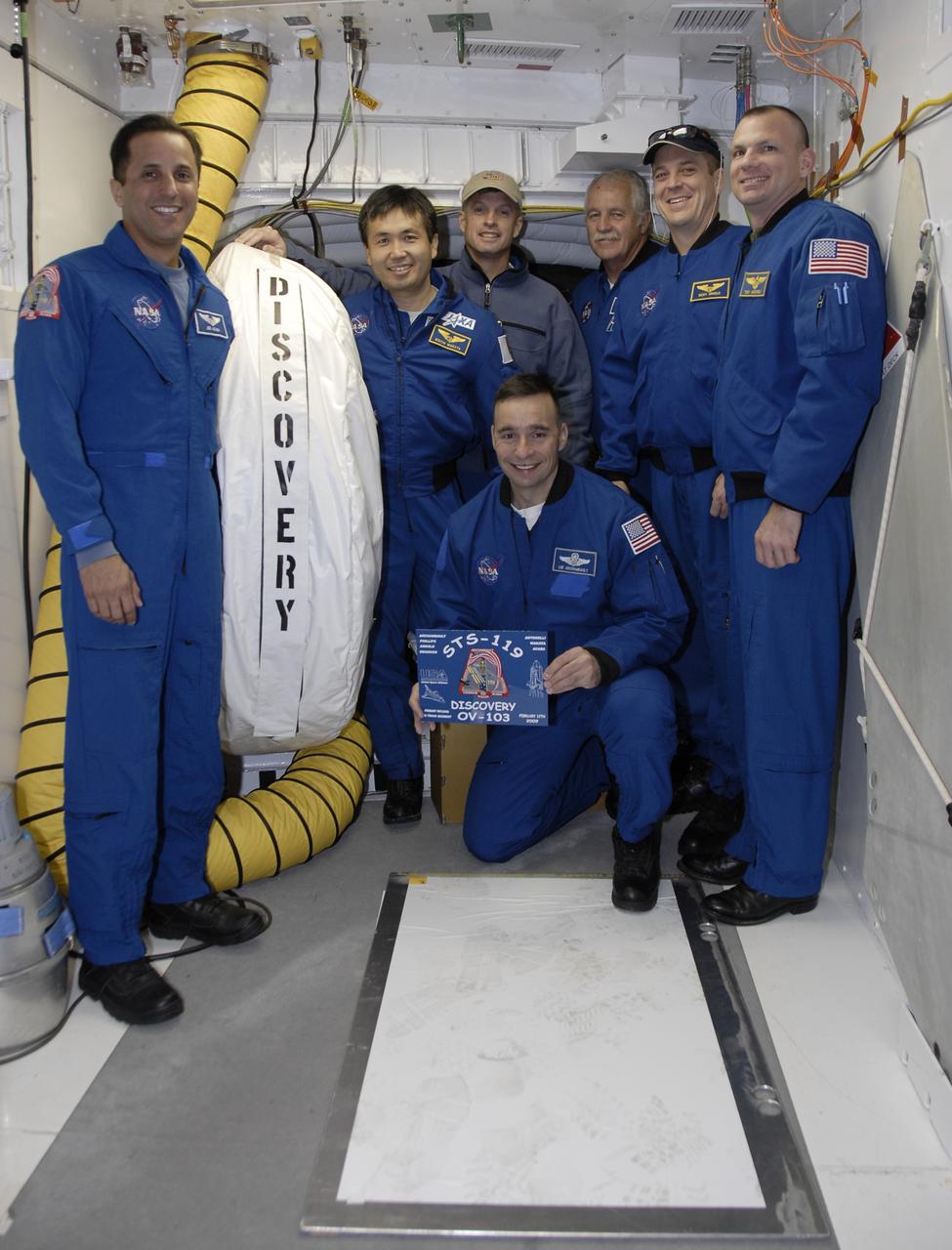 CAPE CANAVERAL, Fla. – The STS-119 crew members gather in front of the hatch into space shuttle Discovery to place the mission plaque. Standing from left are Mission Specialists Joseph Acaba, Koichi Wakata, Steve Swanson, John Phillips and Richard Arnold and Pilot Tony Antonelli. Kneeling in front is Commander Lee Archambault. The astronauts are at Kennedy to prepare for launch as part of the Terminal Countdown Demonstration Test activities. The TCDT includes equipment familiarization and a simulated launch countdown. The crew of space shuttle Discovery is targeted to launch on the STS-119 mission Feb. 12. During Discovery's 14-day mission, the crew will install the S6 truss segment and solar arrays to the starboard side of the International Space Station, completing the station's truss, or backbone. Photo credit: NASA/Kim Shiflett