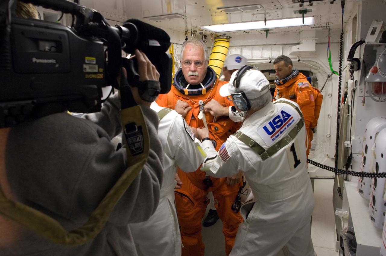 CAPE CANAVERAL, Fla. –  In the White Room on Launch Pad 39A at NASA's Kennedy Space Center in Florida, STS-119 Mission Specialist John Phillips (center) is helped by the Closeout Crew to put on his harness. Phillips will join Commander Lee Archambault (background right) and other crew members to enter space shuttle Discovery to conduct a simulated launch countdown. The astronauts are at Kennedy to prepare for launch through Terminal Countdown Demonstration Test activities. The TCDT includes equipment familiarization and emergency egress training. Discovery is targeted to launch on the STS-119 mission Feb. 12. During the 14-day mission, the crew will install the S6 truss segment and solar arrays to the starboard side of the International Space Station, completing the station's truss, or backbone. Photo credit: NASA/Sandra Joseph, Kevin O'Connell, Tom Farrar
