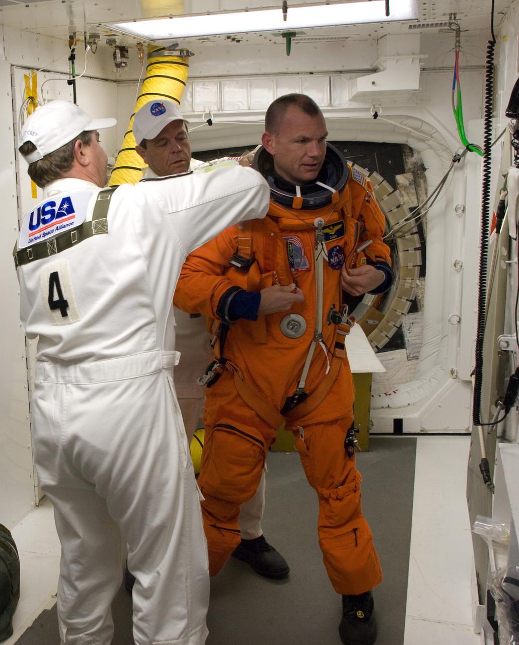 CAPE CANAVERAL, Fla. –  In the White Room on Launch Pad 39A at NASA's Kennedy Space Center in Florida, STS-119 Pilot Tony Antonelli is helped by the Closeout Crew to put on his harness.  Antonelli will enter space shuttle Discovery along with the other crew members to conduct a simulated launch countdown. The astronauts are at Kennedy to prepare for launch through Terminal Countdown Demonstration Test activities. The TCDT includes equipment familiarization and emergency egress training. Discovery is targeted to launch on the STS-119 mission Feb. 12. During the 14-day mission, the crew will install the S6 truss segment and solar arrays to the starboard side of the International Space Station, completing the station's truss, or backbone. Photo credit: NASA/Sandra Joseph, Kevin O'Connell, Tom Farrar