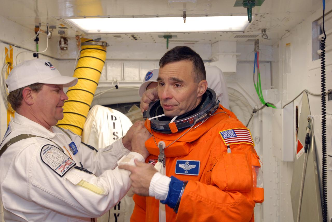 CAPE CANAVERAL, Fla. –   In the White Room on Launch Pad 39A at NASA's Kennedy Space Center in Florida, STS-119 Commander Lee Archambault is helped by the Closeout Crew to put on his harness.  The White Room provides access into space shuttle Discovery.  Archambault and other crew members will conduct a simulated launch countdown as part of the prelaunch preparation known as Terminal Countdown Demonstration Test. The TCDT also includes equipment familiarization and emergency egress training. Discovery is targeted to launch on the STS-119 mission Feb. 12. During the 14-day mission, the crew will install the S6 truss segment and solar arrays to the starboard side of the International Space Station, completing the station's truss, or backbone. Photo credit: NASA/Jim Grossmann