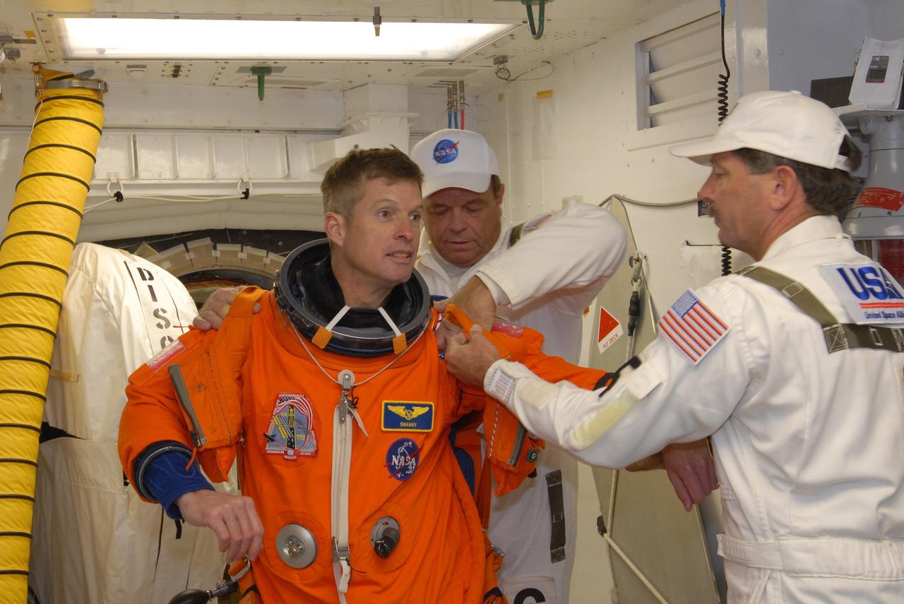 CAPE CANAVERAL, Fla. –  In the White Room on Launch Pad 39A at NASA's Kennedy Space Center in Florida, STS-119 Mission Specialist Steve Swanson is helped by the Closeout Crew to put on his harness.  The White Room provides access into space shuttle Discovery.  Swanson and other crew members will conduct a simulated launch countdown as part of the prelaunch preparation known as Terminal Countdown Demonstration Test.  The TCDT also includes equipment familiarization and emergency egress training. Discovery is targeted to launch on the STS-119 mission Feb. 12. During the 14-day mission, the crew will install the S6 truss segment and solar arrays to the starboard side of the International Space Station, completing the station's truss, or backbone. Photo credit: NASA/Jim Grossmann