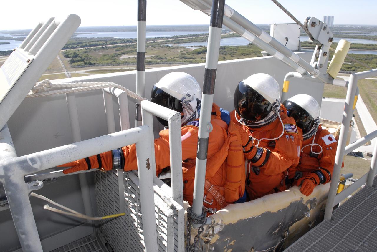 CAPE CANAVERAL, Fla. –  Following the simulated launch countdown on Launch Pad 39A at NASA's Kennedy Space Center in Florida, STS-119 crew members are in the slidewire basket they would use during an emergency egress.  The slidewire basket could propel them to a landing area below, if needed. The practice egress is part of the prelaunch preparation known as Terminal Countdown Demonstration Test.  The TCDT also includes equipment familiarization. Discovery is targeted to launch on the STS-119 mission Feb. 12. During the 14-day mission, the crew will install the S6 truss segment and solar arrays to the starboard side of the International Space Station, completing the station's truss, or backbone. Photo credit: NASA/Kim Shiflett