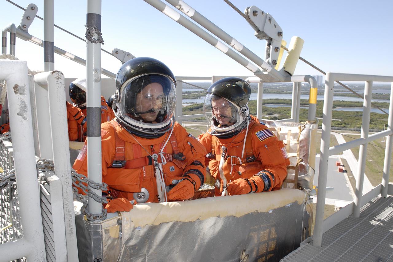 CAPE CANAVERAL, Fla. –  Following the simulated launch countdown on Launch Pad 39A at NASA's Kennedy Space Center in Florida, STS-119 Mission Specialists Joseph Acaba (left) and Richard Arnold  practice emergency egress from the pad.  They are seated in a slidewire basket that could propel them to a landing area below.  The countdown and emergency egress are part of the prelaunch preparation known as Terminal Countdown Demonstration Test. The TCDT also includes equipment familiarization. Discovery is targeted to launch on the STS-119 mission Feb. 12. During the 14-day mission, the crew will install the S6 truss segment and solar arrays to the starboard side of the International Space Station, completing the station's truss, or backbone. Photo credit: NASA/Kim Shiflett