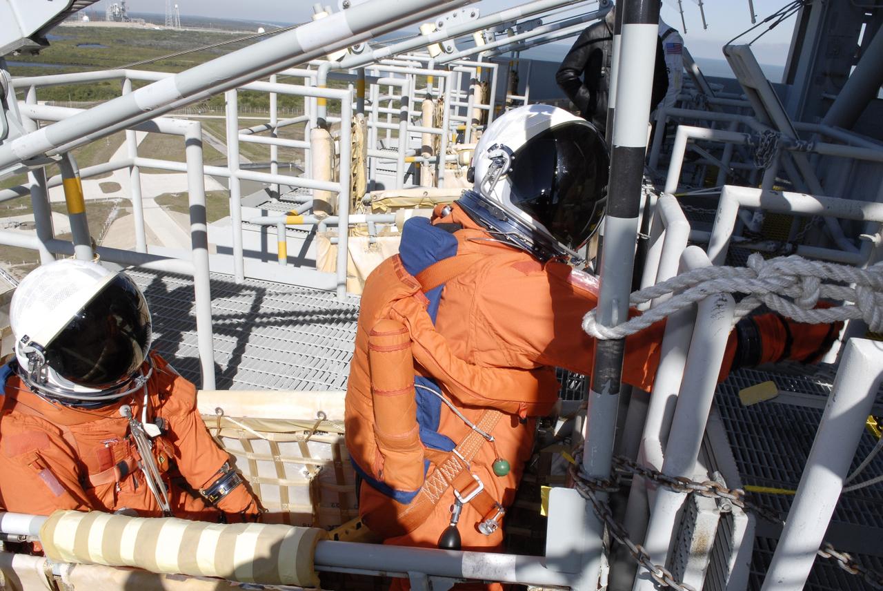 CAPE CANAVERAL, Fla. –  Following the simulated launch countdown on Launch Pad 39A at NASA's Kennedy Space Center in Florida, STS-119 crew members are in the slidewire basket they would use during an emergency egress.  The slidewire basket could propel them to a landing area below, if needed. The practice egress is part of the prelaunch preparation known as Terminal Countdown Demonstration Test.  The TCDT also includes equipment familiarization. Discovery is targeted to launch on the STS-119 mission Feb. 12. During the 14-day mission, the crew will install the S6 truss segment and solar arrays to the starboard side of the International Space Station, completing the station's truss, or backbone. Photo credit: NASA/Kim Shiflett
