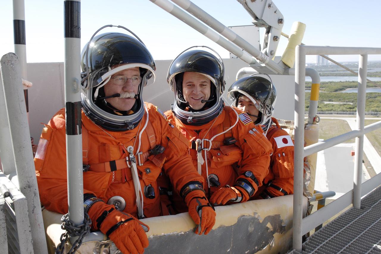 CAPE CANAVERAL, Fla. –  Following the simulated launch countdown on Launch Pad 39A at NASA's Kennedy Space Center in Florida, STS-119 crew members are in the slidewire basket they would use during an emergency egress.  The slidewire basket could propel them to a landing area below, if needed. From left are Mission Specialists John Phillips, Richard Arnold and Koichi Wakata. The practice egress is part of the prelaunch preparation known as Terminal Countdown Demonstration Test. The TCDT also includes equipment familiarization. Discovery is targeted to launch on the STS-119 mission Feb. 12. During the 14-day mission, the crew will install the S6 truss segment and solar arrays to the starboard side of the International Space Station, completing the station's truss, or backbone. Photo credit: NASA/Kim Shiflett