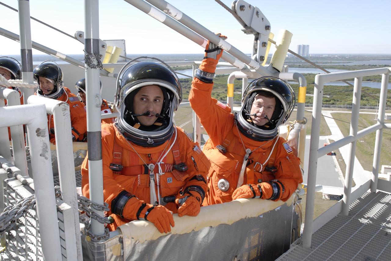 CAPE CANAVERAL, Fla. –  Following the simulated launch countdown on Launch Pad 39A at NASA's Kennedy Space Center in Florida, STS-119 Mission Specialists Joseph Acaba (left) and Richard Arnold are seated in a slidewire basket that could propel them to a landing area below.  The slidewire basket is used for emergency egress from the pad. In the background at left are Mission Specialists Richard Arnold and Koichi Wakata. The countdown and emergency egress are part of the prelaunch preparation known as Terminal Countdown Demonstration Test.  The TCDT also includes equipment familiarization. Discovery is targeted to launch on the STS-119 mission Feb. 12. During the 14-day mission, the crew will install the S6 truss segment and solar arrays to the starboard side of the International Space Station, completing the station's truss, or backbone. Photo credit: NASA/Kim Shiflett