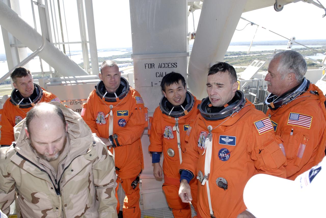CAPE CANAVERAL, Fla. – On Launch Pad 39A at NASA's Kennedy Space Center in Florida, STS-119 crew members gather around the slidewire baskets used for emergency egress from the pad. From left are Mission Specialist Steve Swanson, Pilot Tony Antonelli, Mission Specialist Koichi Wakata, Commander Lee Archambault and Mission Specialist John Phillips. Practicing emergency egress is part of the prelaunch preparation known as Terminal Countdown Demonstration Test. The TCDT also includes equipment familiarization. Discovery is targeted to launch on the STS-119 mission Feb. 12. During the 14-day mission, the crew will install the S6 truss segment and solar arrays to the starboard side of the International Space Station, completing the station's truss, or backbone. Photo credit: NASA/Kim Shiflett